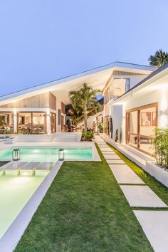 a house with a swimming pool in the front yard and landscaping on the other side