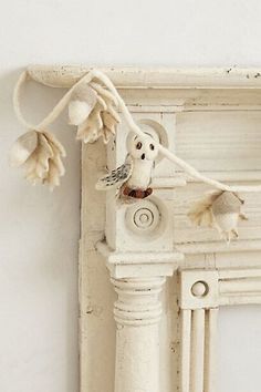 a white bird is perched on the corner of a window sill with flowers hanging from it's side