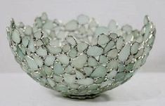 a glass bowl that is sitting on a white tablecloth with silver wirework around it