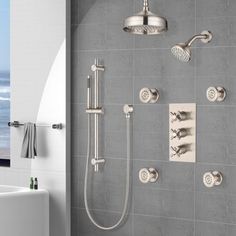 the shower head and handset are shown in this bathroom with grey tile walls, white fixtures