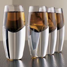 four glasses filled with liquid sitting on top of a table