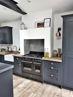 a kitchen with gray cabinets and an oven in the center is seen from across the room