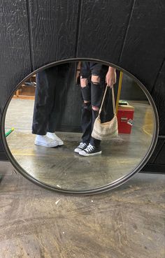 a person standing in front of a mirror holding a handbag and looking at their reflection