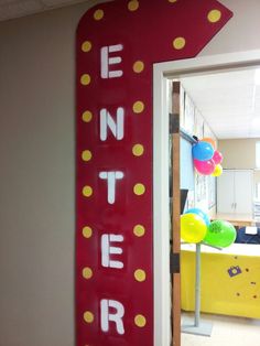 a red sign that says enter in front of a room with yellow and blue balloons