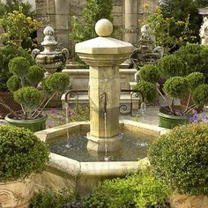 an outdoor fountain surrounded by potted plants