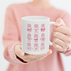 a woman is holding a coffee mug with pink bows on the front and back of it