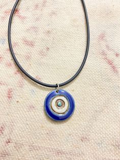 a blue and white necklace sitting on top of a piece of cloth with an evil eye in the center