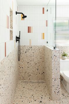 a tiled bathroom with a shower, toilet and window in the backround area