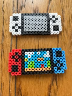 two lego magnets sitting on top of a wooden table next to each other with different colored beads