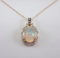 "Yellow Gold Diamond and Opal Pendant Necklace. The Necklace is set with one Oval Opal Cabochon in the center.  This Opal measures 10 X 8 mm and weighs 1 1/2 carats.  There are three Round Brilliant Champagne Diamonds and twenty-five Round Brilliant white/colorless Diamonds set in this pendant. These diamonds are H color (white), I1 clarity and weigh a total of .18 carat.  The pendant is 10K Yellow Gold and comes with an 18\" 10K Yellow Gold chain and together weigh 1.9 grams.  The pendant measu Classic Round Necklace With Accent Stones, Luxury Round Necklaces With Accent Stones, Classic Round Necklaces With Accent Stones, Gold Necklace With Round Accent Stones, Yellow Gold Oval Necklace With Accent Stones, Classic White Jewelry With Gemstone Accents, Oval Multi-stone Necklace For Wedding, Oval Yellow Gold Necklace With Accent Stones, Classic Round Multi-stone Necklaces