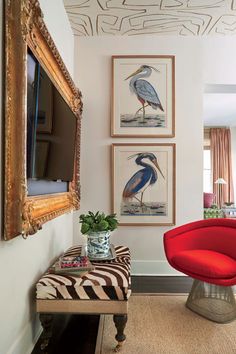 a living room with pictures on the wall and a red chair in front of it