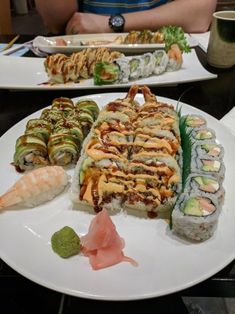 two plates with sushi and rolls on them