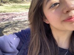 a close up of a person with a hot dog in front of her and trees