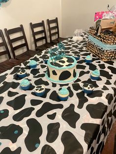 a cow print table cloth with cupcakes on it