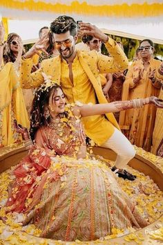 a man and woman in yellow outfits dancing on a bed of flowers with other people behind them