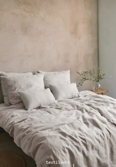 an unmade bed with white linens and pillows