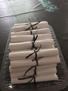 a stack of white napkins with black ribbon tied around them on a clear platter