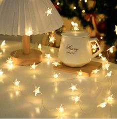 a tea pot and lamp on a table in front of a christmas tree with lights