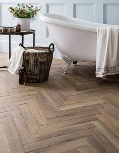 a bath tub sitting on top of a wooden floor next to a table with flowers