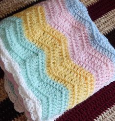 three crocheted blankets are stacked on top of each other, one is multicolored