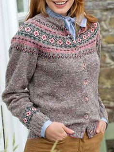 a woman standing in front of a building wearing a sweater