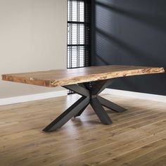 a wooden table sitting on top of a hard wood floor next to a black wall