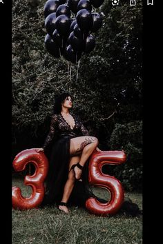 a woman sitting on top of a red number 35 balloon