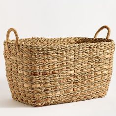 a large woven basket with handles on the bottom and two handles at the top, sitting against a white background