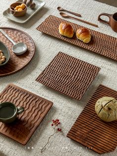 a table topped with plates and bowls filled with pastries next to bread on top of wooden trays