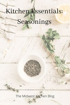 a white bowl filled with herbs on top of a wooden table next to an orange slice