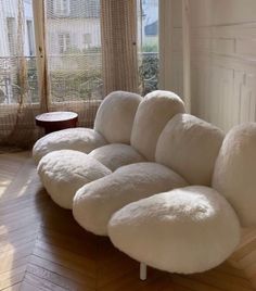 a large white couch sitting on top of a hard wood floor next to a window