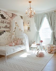 a room with a white bed, chandelier and pink decorations