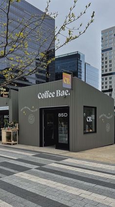 an empty coffee shop on the corner of a street with tall buildings in the background