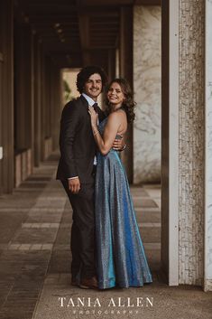 a man and woman standing next to each other in front of a building with columns