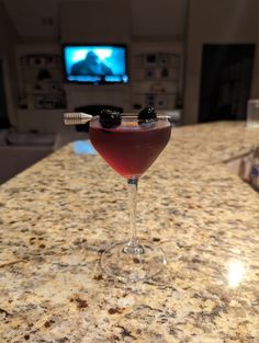 a close up of a wine glass on a counter with a tv in the background