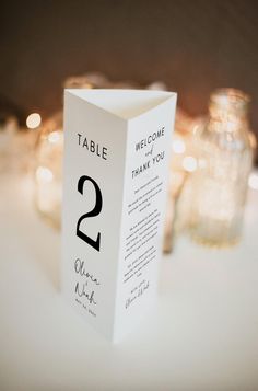 a table number card sitting on top of a table next to some jars and candles