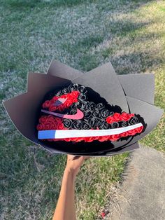 someone is holding up a cake in the shape of a nike shoe with roses on it