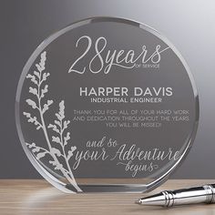 a clear glass award with the words 25 years on it and a pen next to it