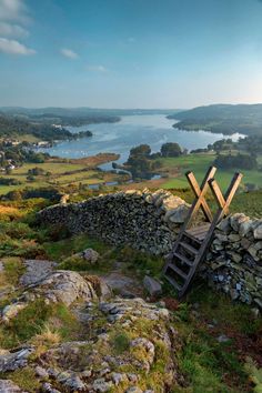 a ladder leaning against a stone wall on top of a hill next to a body of water