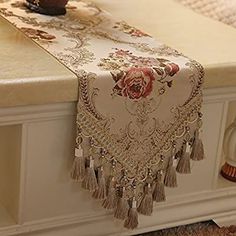 a table runner with tassels and flowers on it