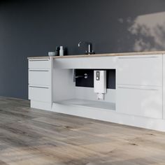 a kitchen with white cabinets and wood flooring in front of a gray painted wall