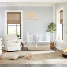 a baby's room with a white crib, rocking chair and window blinds