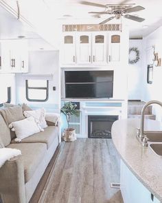 a living room and kitchen area in a recreational vehicle or camper with wood flooring