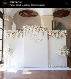 an image of a wedding ceremony with flowers on the back wall and white paper in front of it