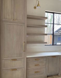 a kitchen with wooden cabinets and white counter tops in front of a large open window