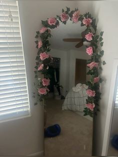 a mirror with pink flowers hanging from it's sides in a room next to a window