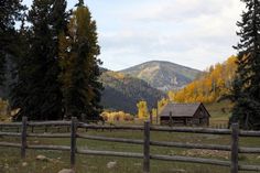 an old log cabin in the mountains surrounded by trees