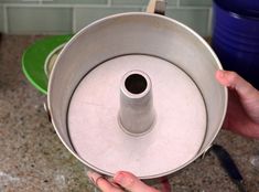 a person holding a metal pan over a stove top