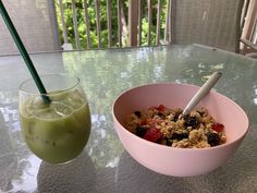 a bowl of oatmeal and a glass of green smoothie on a table