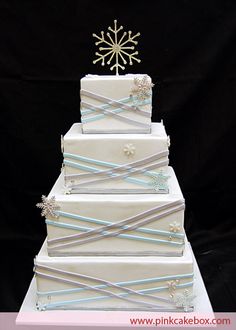 a three tiered white cake with snowflakes on top